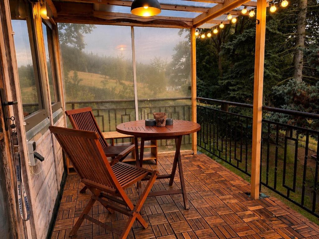 Überdachter Balkon mit Holzmöbeln und warmer Lichterkette am Abend