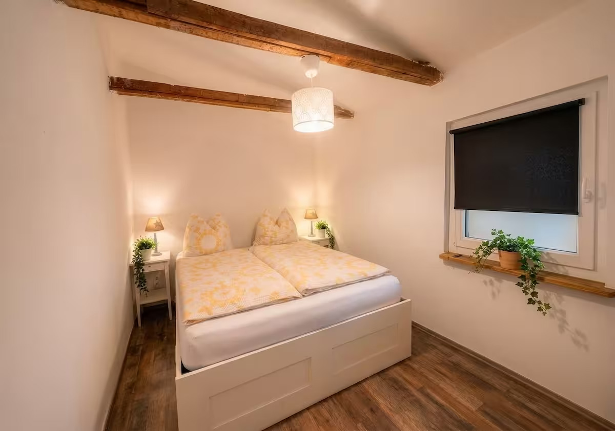 Schlafzimmer der Unterkunft mit Doppelbett und sichtbaren Holzbalken